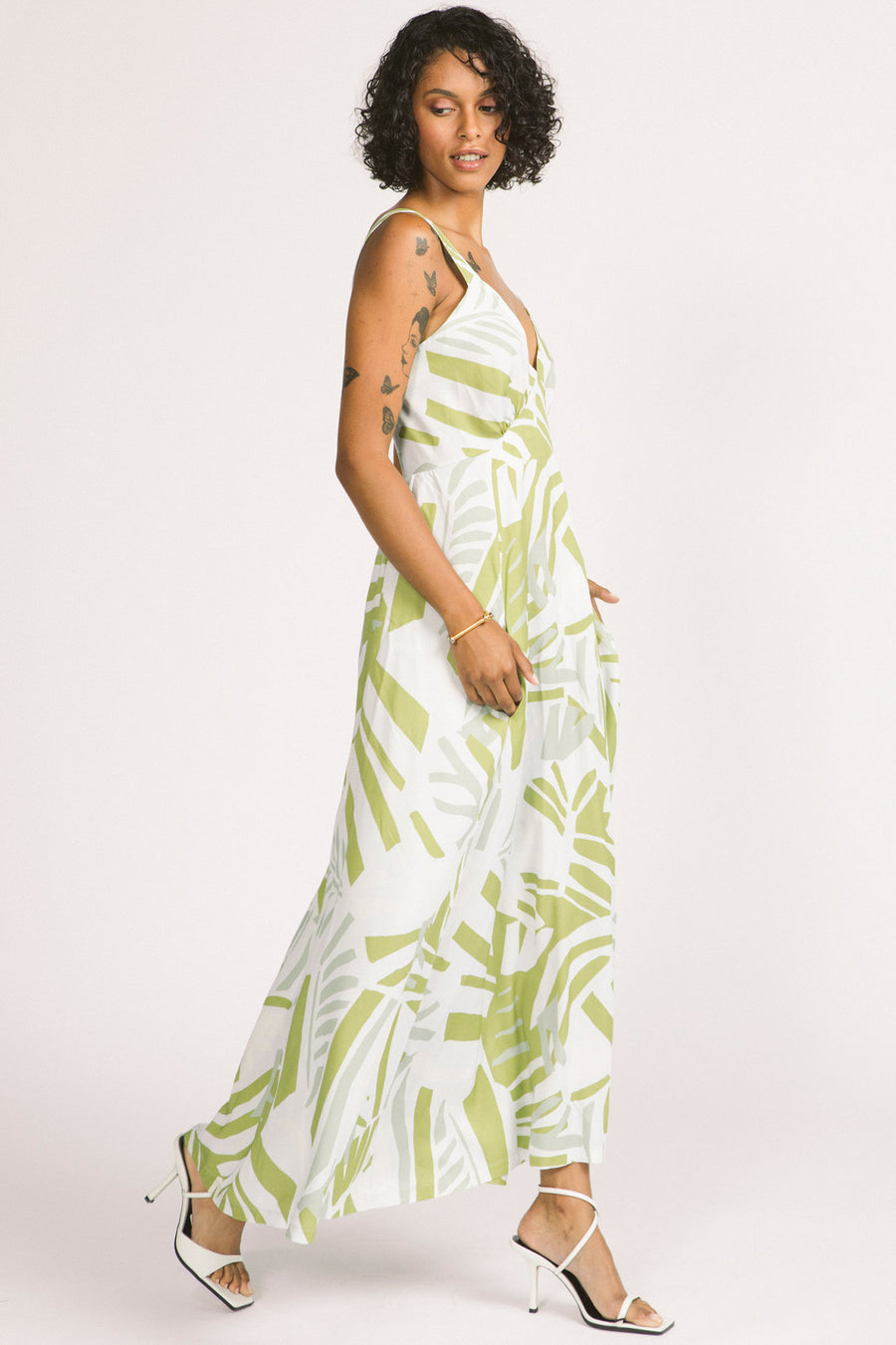 Side view of woman wearing green and white leaf print Alora maxi dress by Allison Wonderland. 