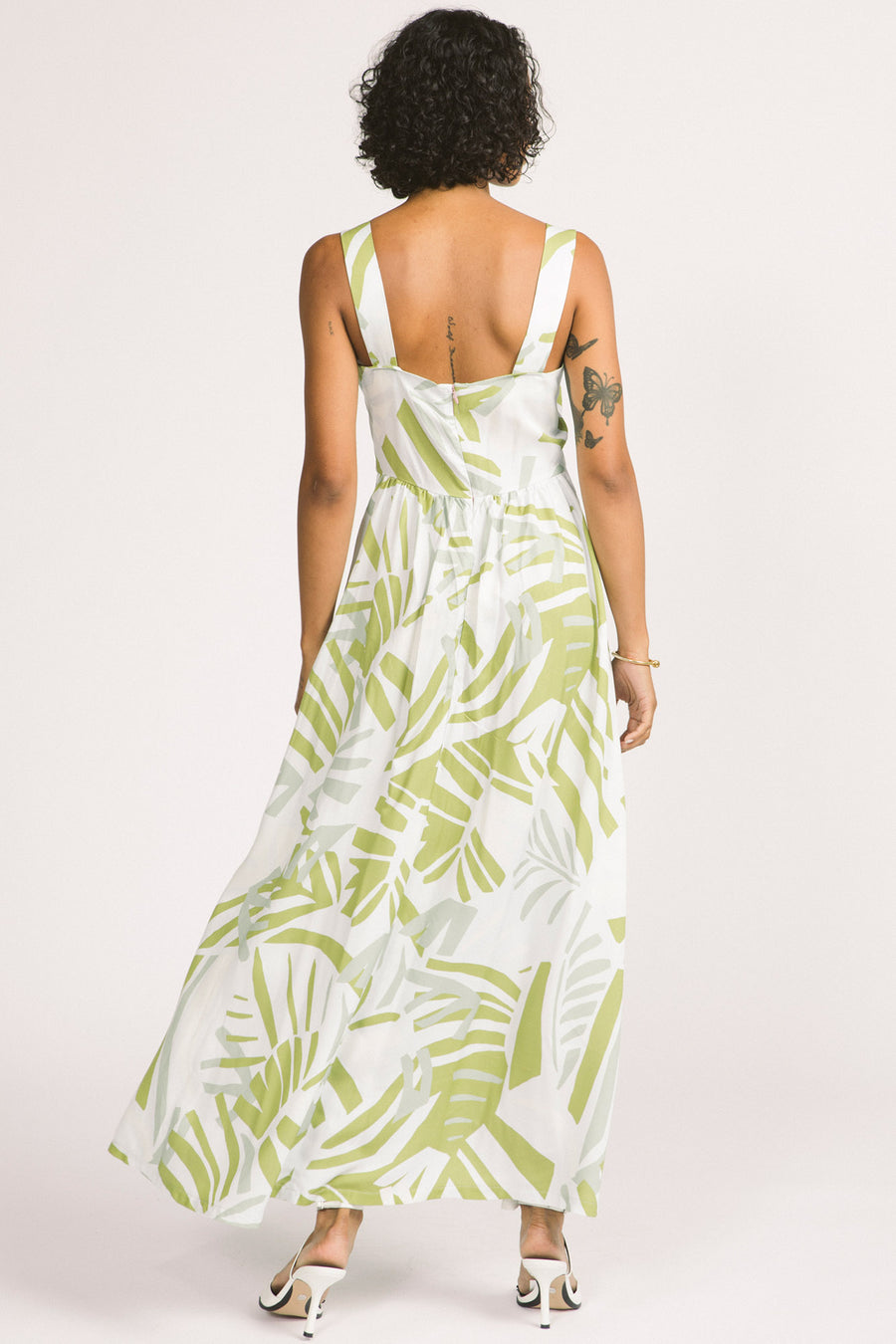 Back view of woman wearing green and white leaf print Alora maxi dress by Allison Wonderland. 