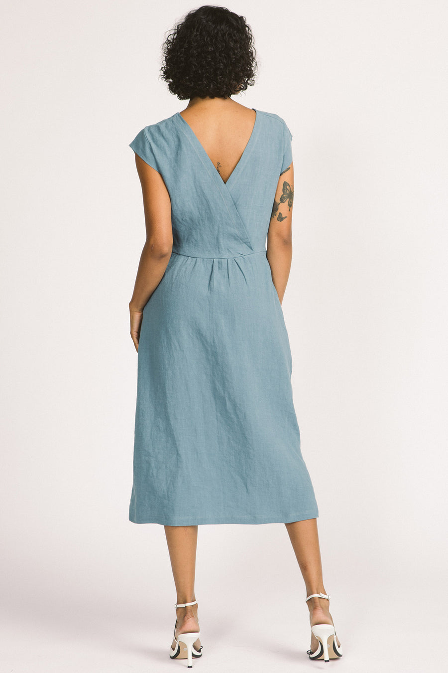 Back view of woman wearing sky blue button up linen midi Blythe dress by Allison Wonderland. 