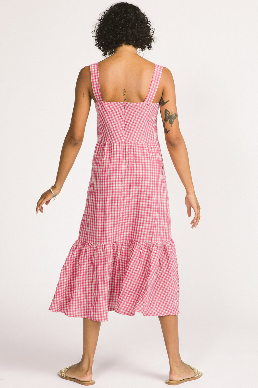 Back view of woman wearing pink and white linen gingham tiered Calista summer dress by Allison Wonderland. 