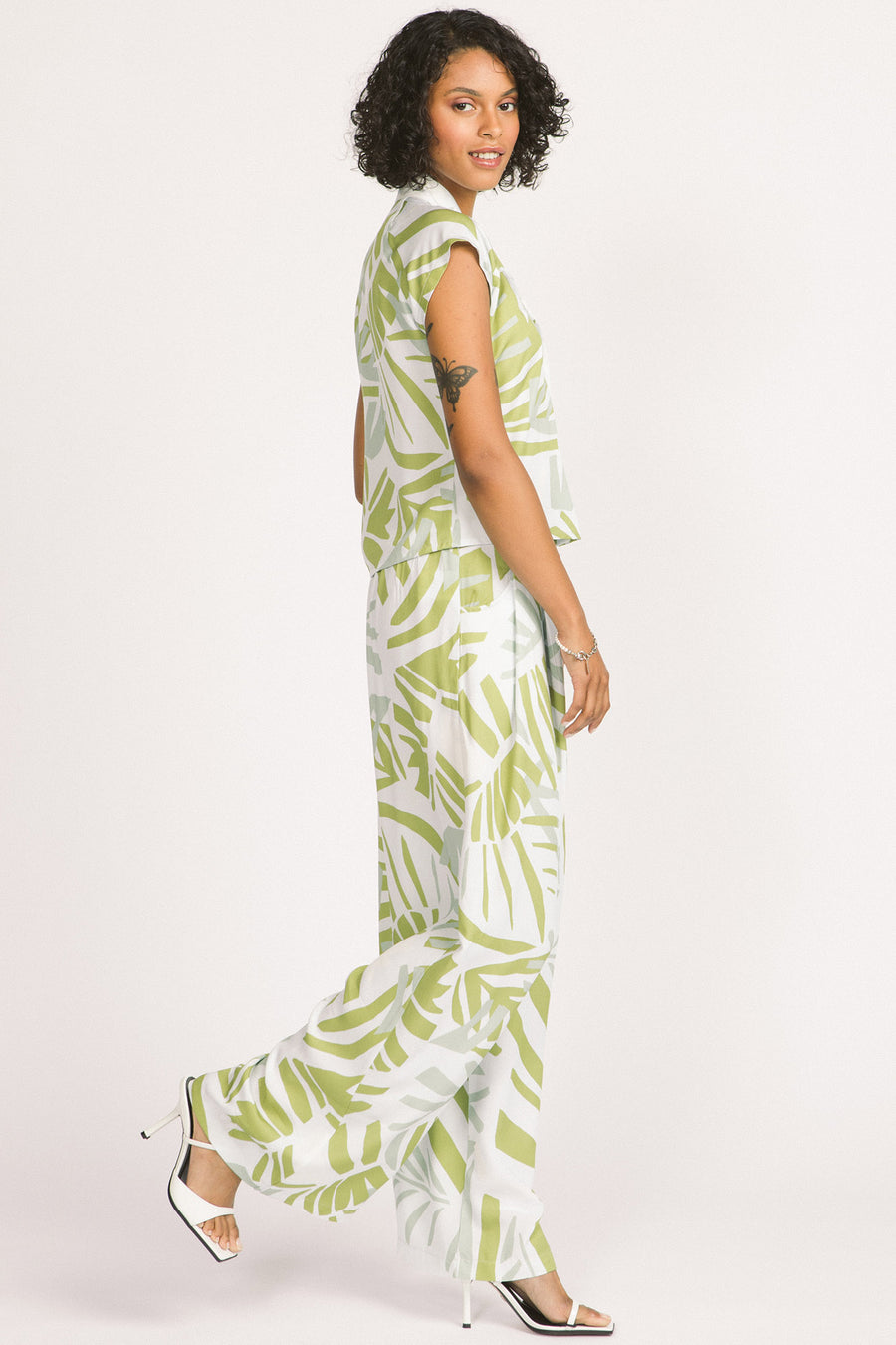 Side view of woman wearing green and white frond leaf print Darcy pants by Allison Wonderland. 