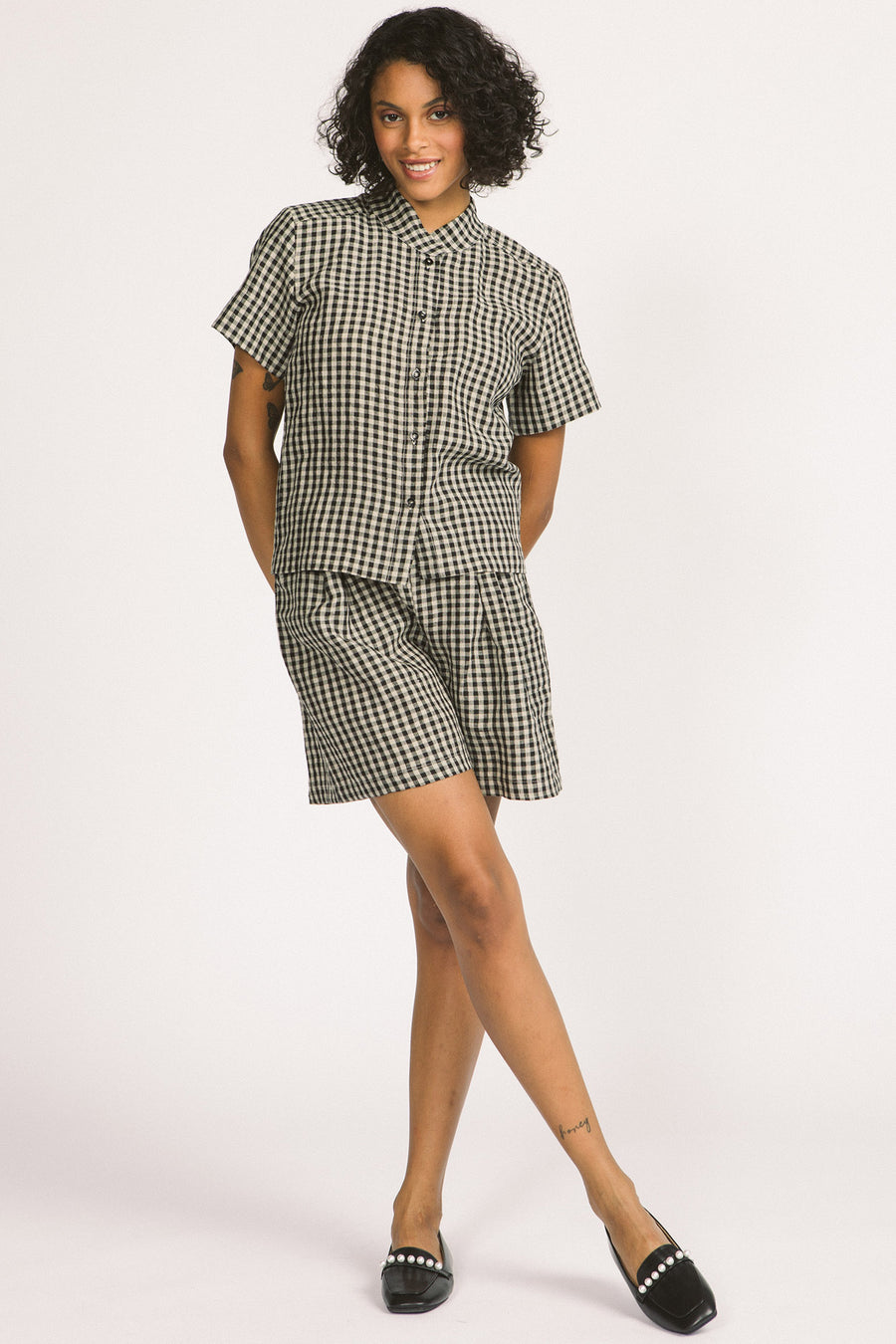 Woman wearing a black and white linen gingham button up Elodie blouse by Allison Wonderland. 