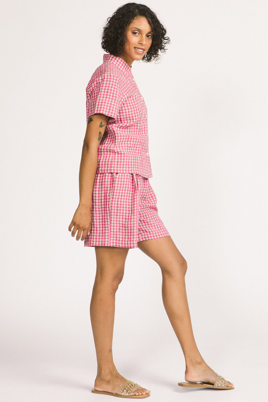 Side view of woman wearing a pink and white linen gingham button up Elodie blouse by Allison Wonderland. 