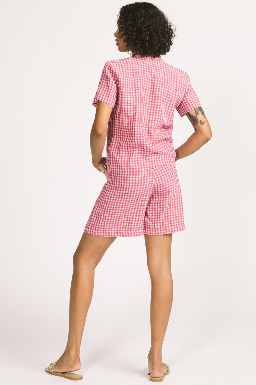 Back view of woman wearing a pink and white linen gingham button up Elodie blouse by Allison Wonderland. 