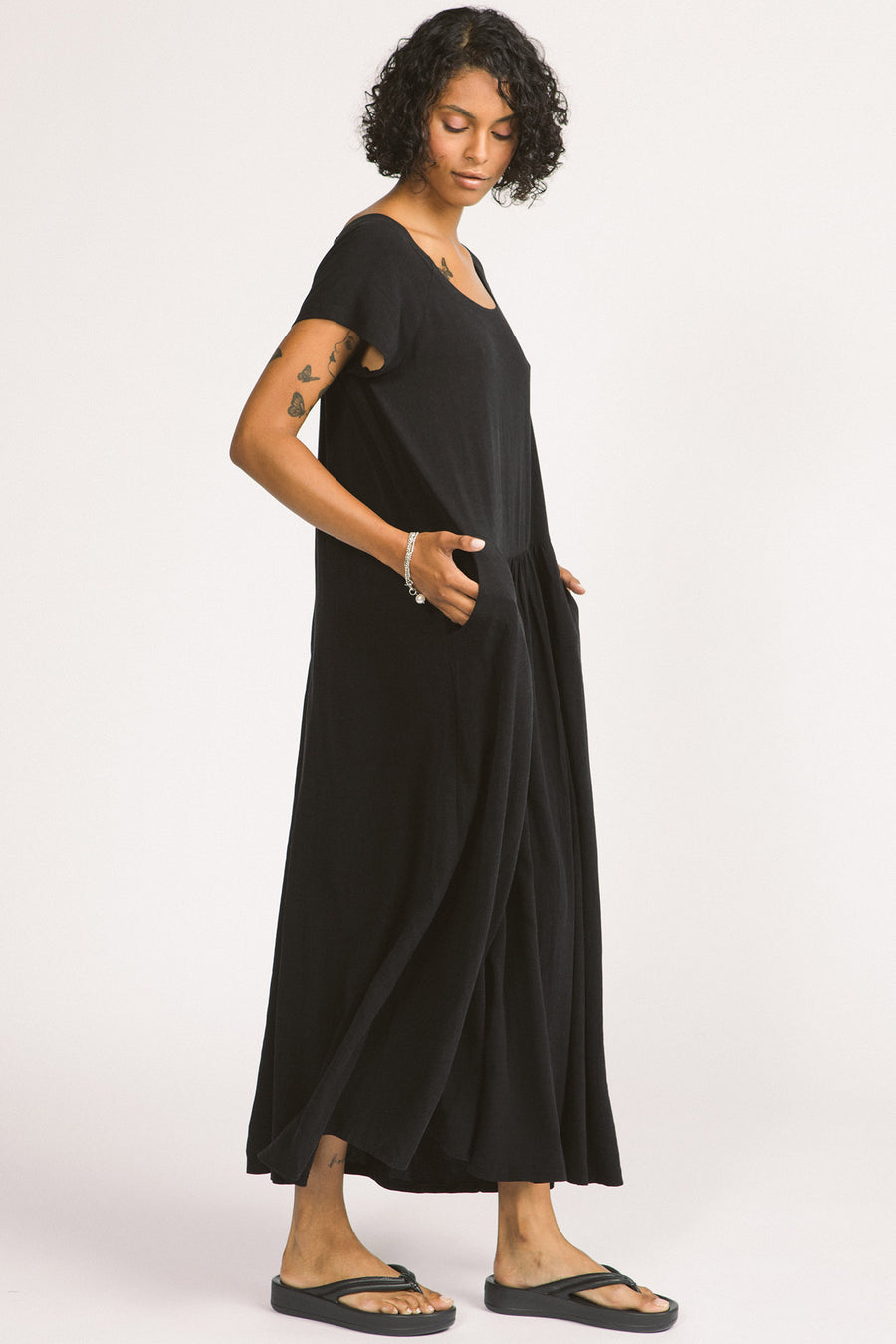 Side view of woman wearing black maxi Allison Wonderland Enola Dress. 