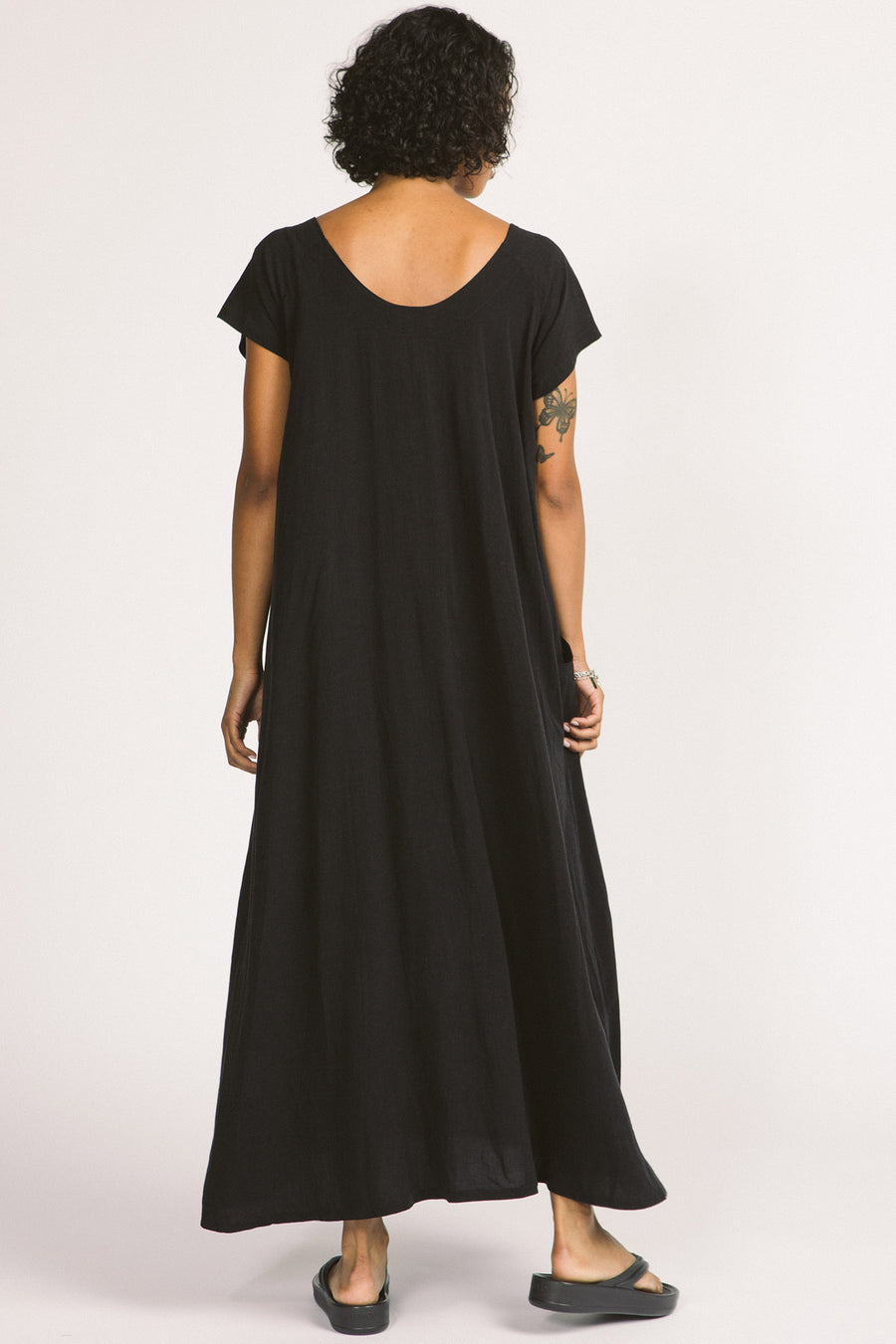 Back view of woman wearing black maxi Allison Wonderland Enola Dress. 