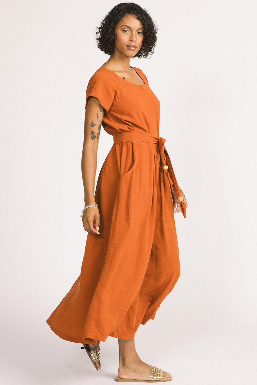 Side view of woman wearing cognac maxi Allison Wonderland Enola Dress tied of waist.. 
