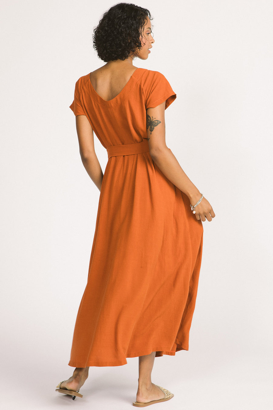 Back view of woman wearing cognac maxi Allison Wonderland Enola Dress tied of waist..