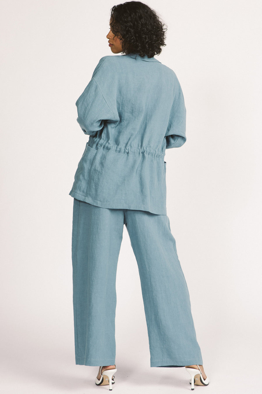 Back view of woman wearing sky blue linen drawstring Greer blazer by Allison Wonderland. 