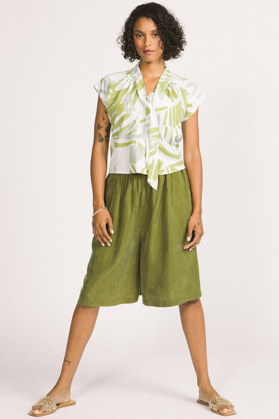 Woman wearing a green and white leaf print Isabeau blouse by Allison Wonderland. 