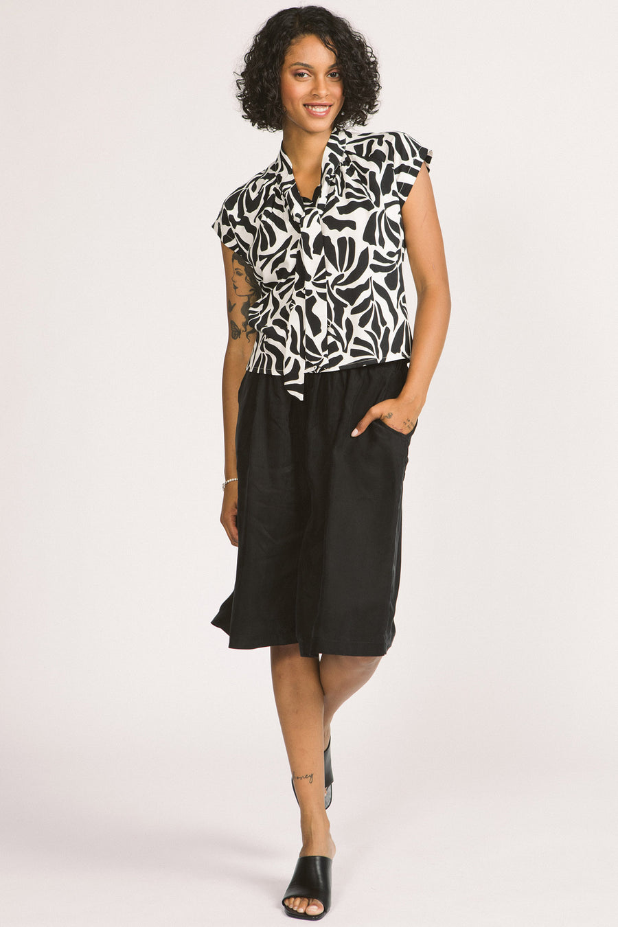 Woman wearing a black and white leaf print Isabeau blouse by Allison Wonderland. 