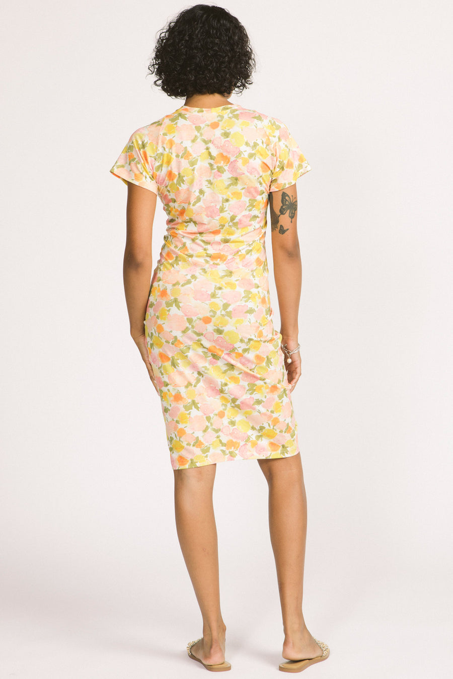 Back view of woman wearing yellow floral bodycon Jessamine dress by Allison Wonderland. 
