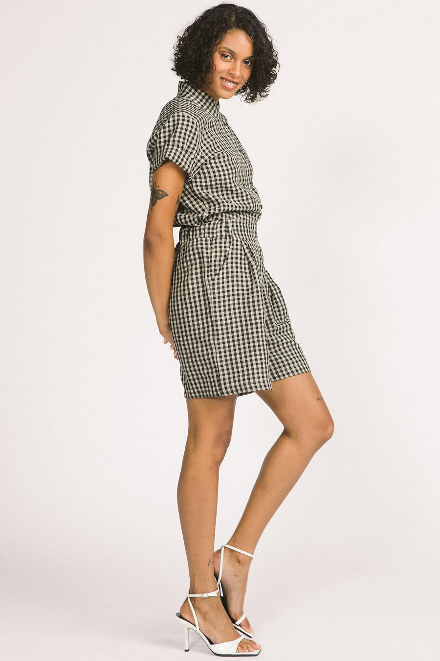 Side view of woman wearing black and white gingham Kim shorts by Allison Wonderland. 