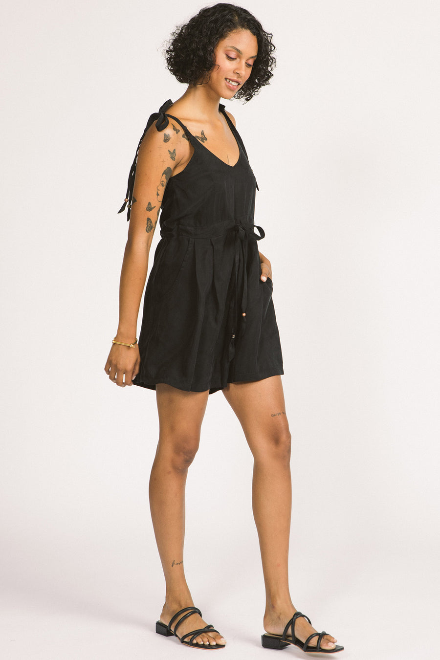 Woman wearing black short Meara short romper by Allison Wonderland. 