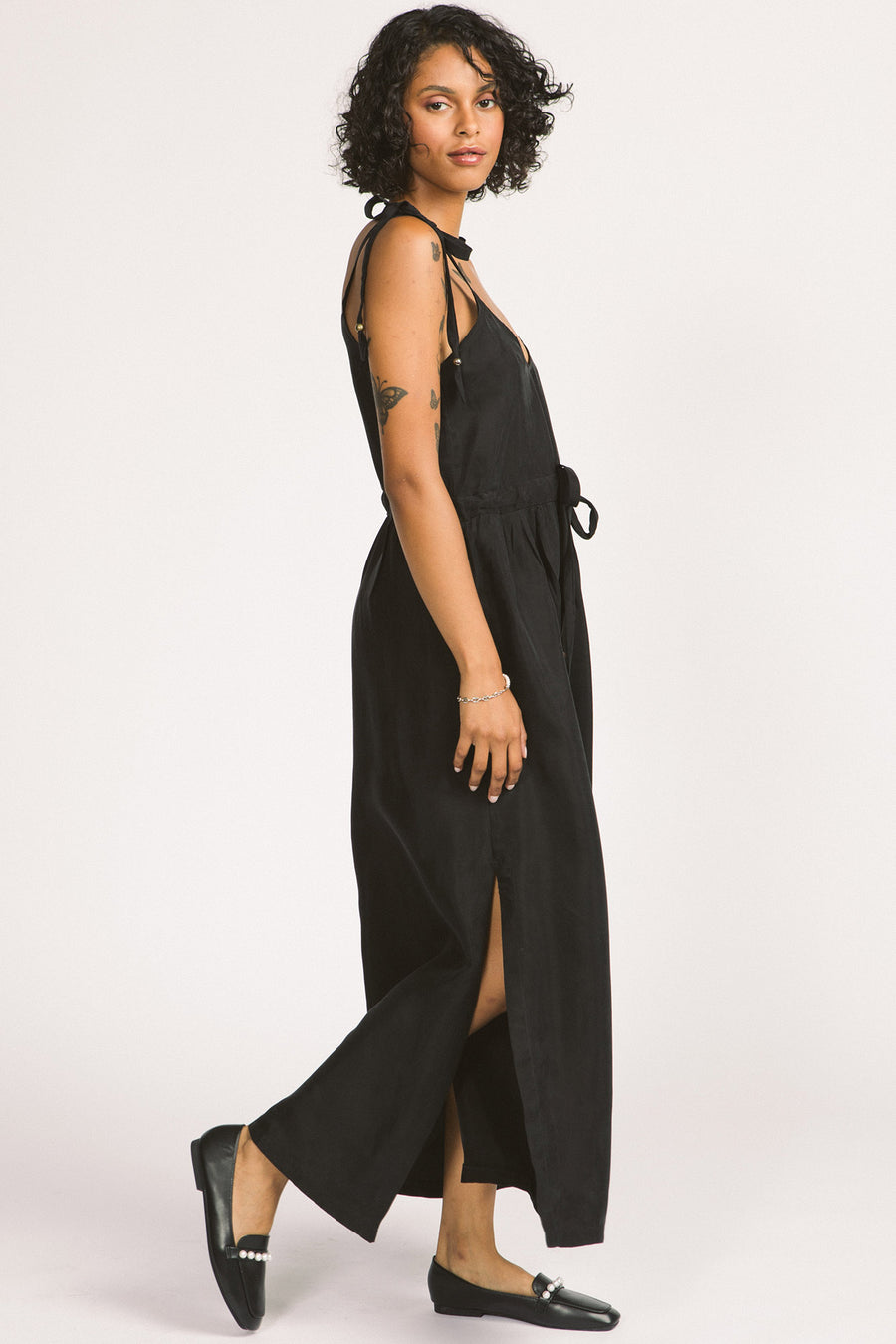 Side view of woman wearing black Novalie dress by Allison Wonderland with adjustable shoulder straps and waist. 