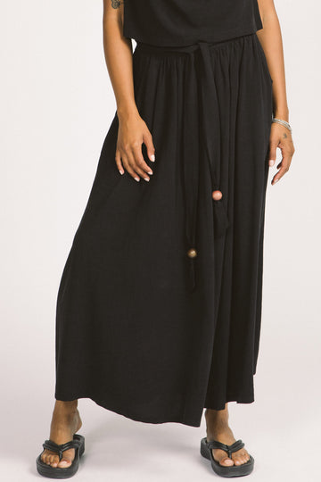 Close-up of woman wearing black Oriana maxi skirt by Allison Wonderland. 
