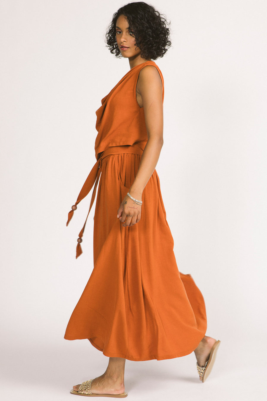 Side view of woman wearing orange cognac Oriana maxi skirt by Allison Wonderland. 