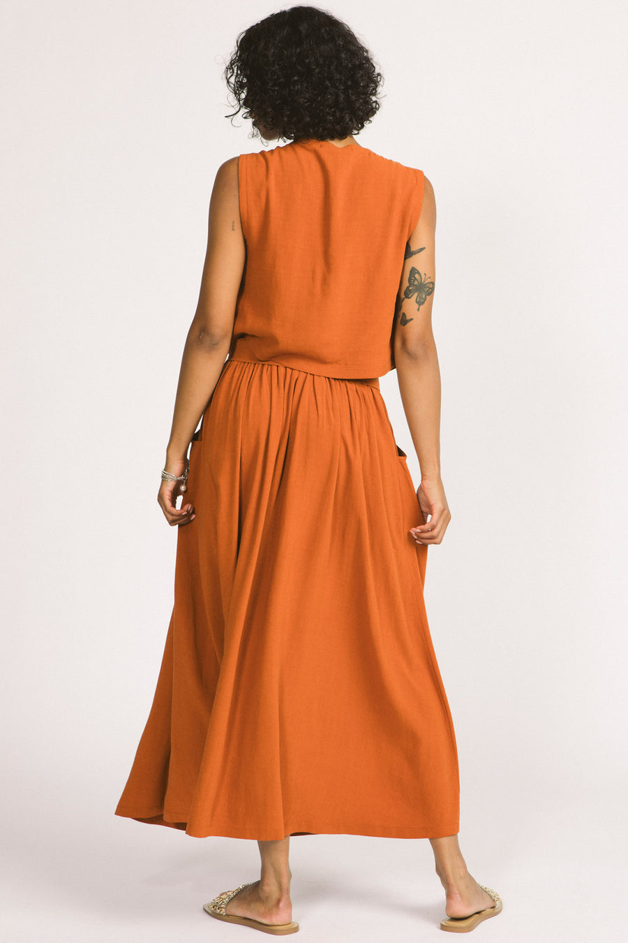 Back view of woman wearing orange cognac Oriana maxi skirt by Allison Wonderland. 