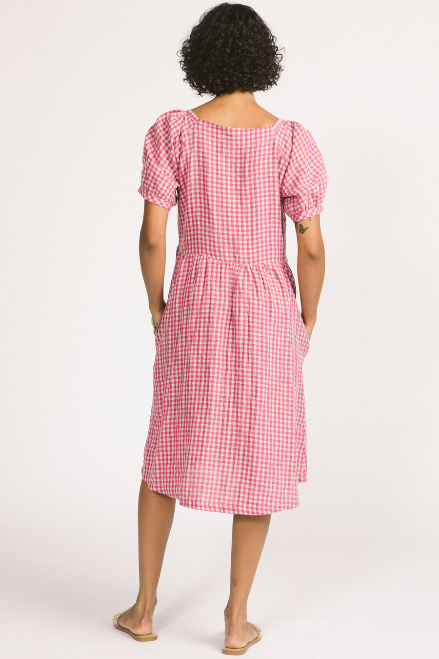 Back view of woman wearing pink and white linen gingham oversized babydoll Verity dress. 