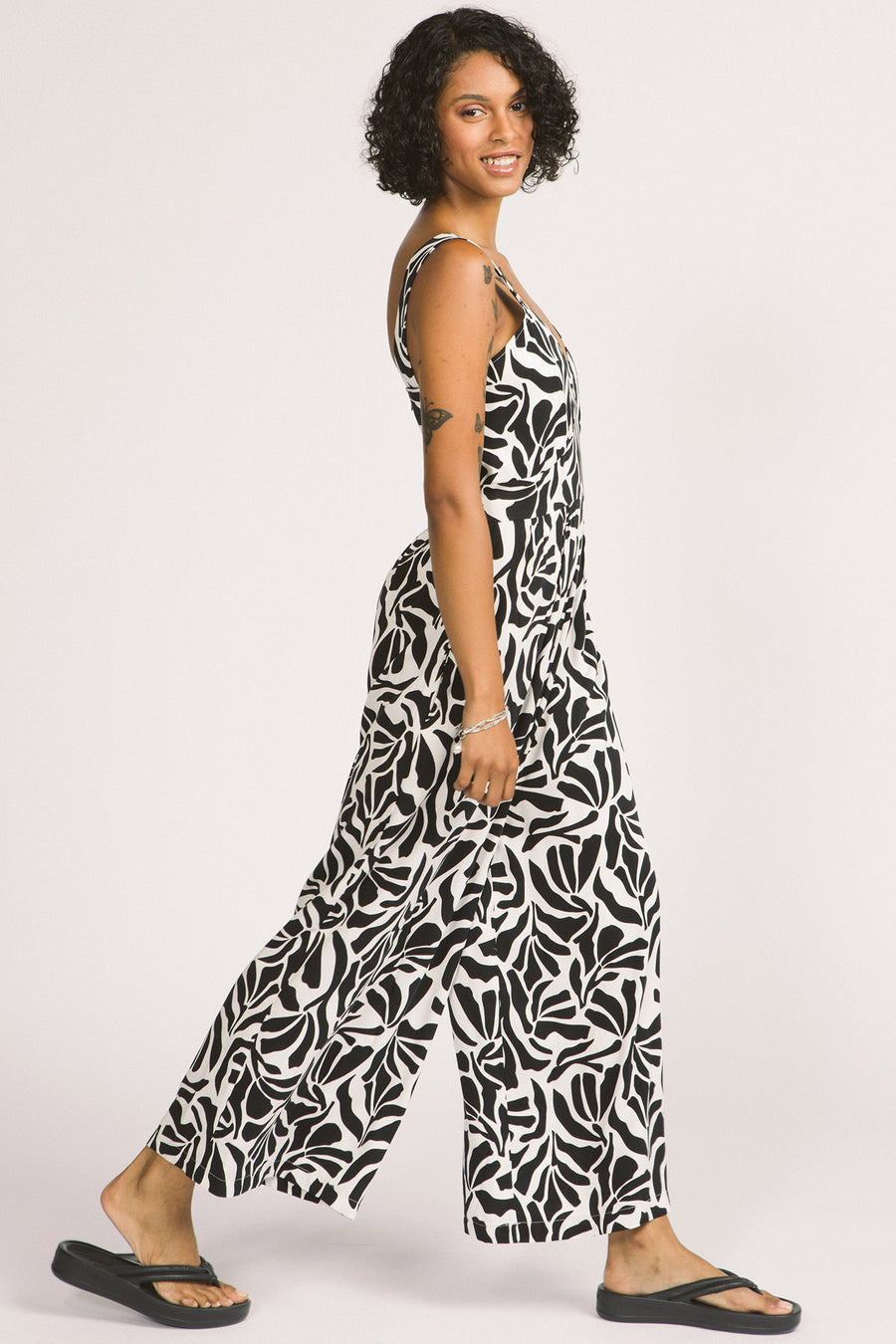 Side view of woman wearing black and white zebra leaf print Zadie jumpsuit by Allison Wonderland. 