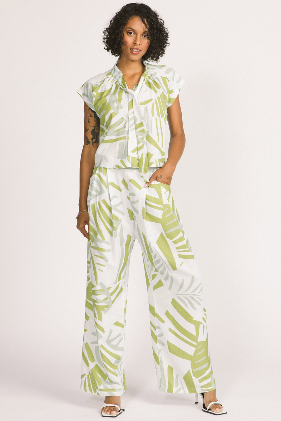 Woman wearing green and white frond leaf print Darcy pants by Allison Wonderland. 