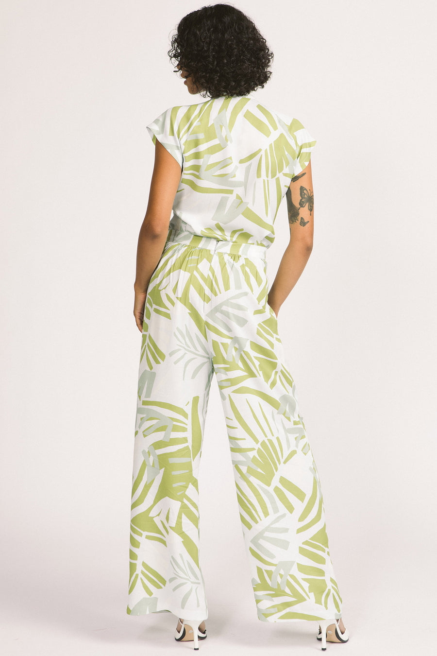 Back view of woman wearing green and white frond leaf print Darcy pants by Allison Wonderland. 