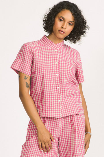 Woman wearing a pink and white linen gingham button up Elodie blouse by Allison Wonderland. 