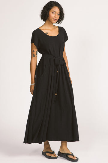 Woman wearing black maxi Allison Wonderland Enola Dress tied at waist. 