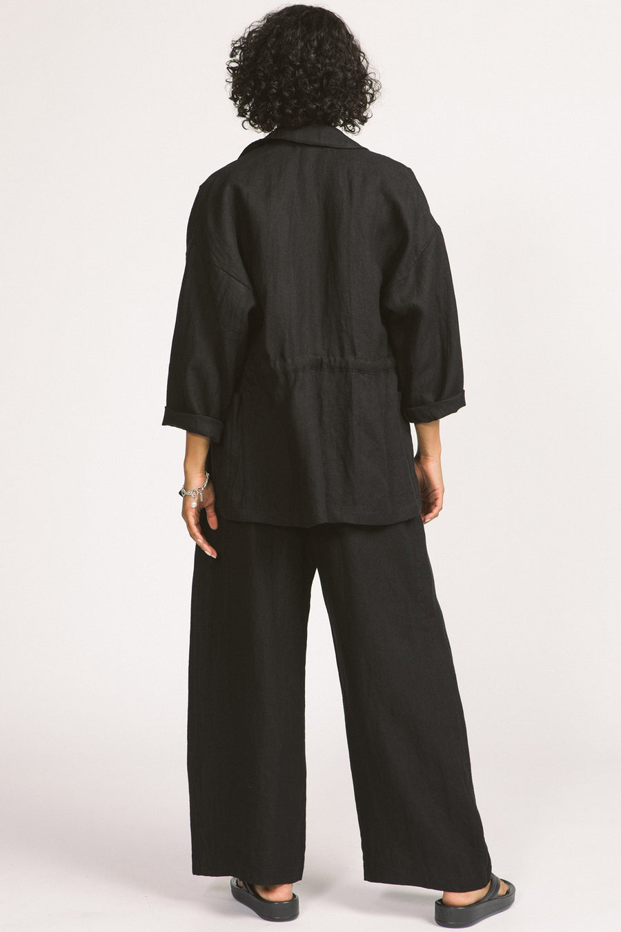 Back view of woman wearing black linen drawstring Greer blazer by Allison Wonderland. 