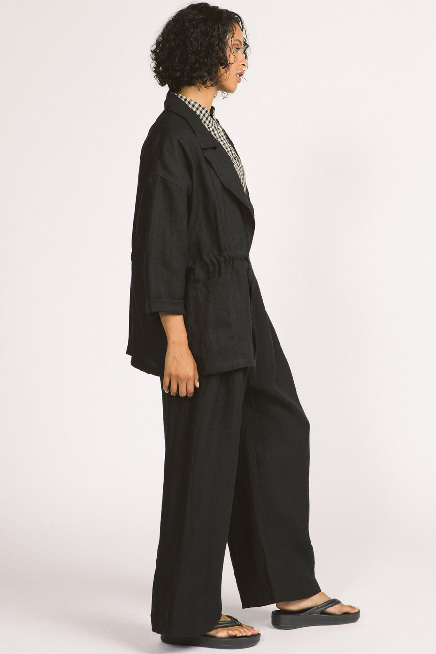 Side view of woman wearing black linen drawstring Greer blazer by Allison Wonderland. 