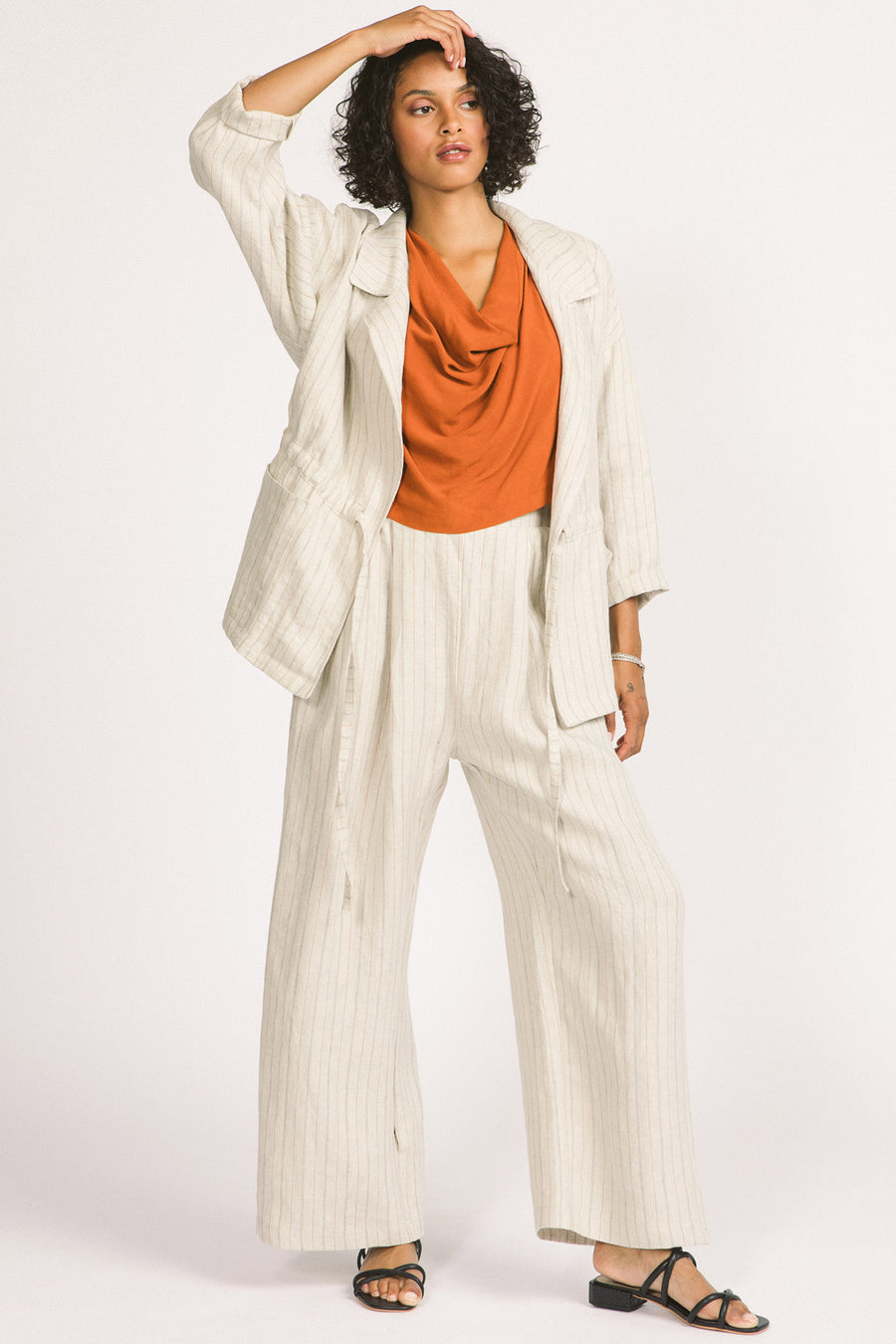 Woman wearing ivory stripe linen wide leg Romy pants and Greer blazer by Allison Wonderland. 
