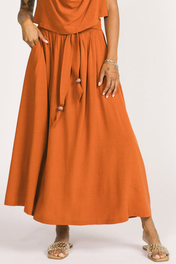 Closeup of woman wearing orange cognac Oriana maxi skirt by Allison Wonderland. 