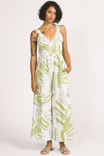 Woman wearing green and white frond leaf print Zadie jumpsuit by Allison Wonderland. 