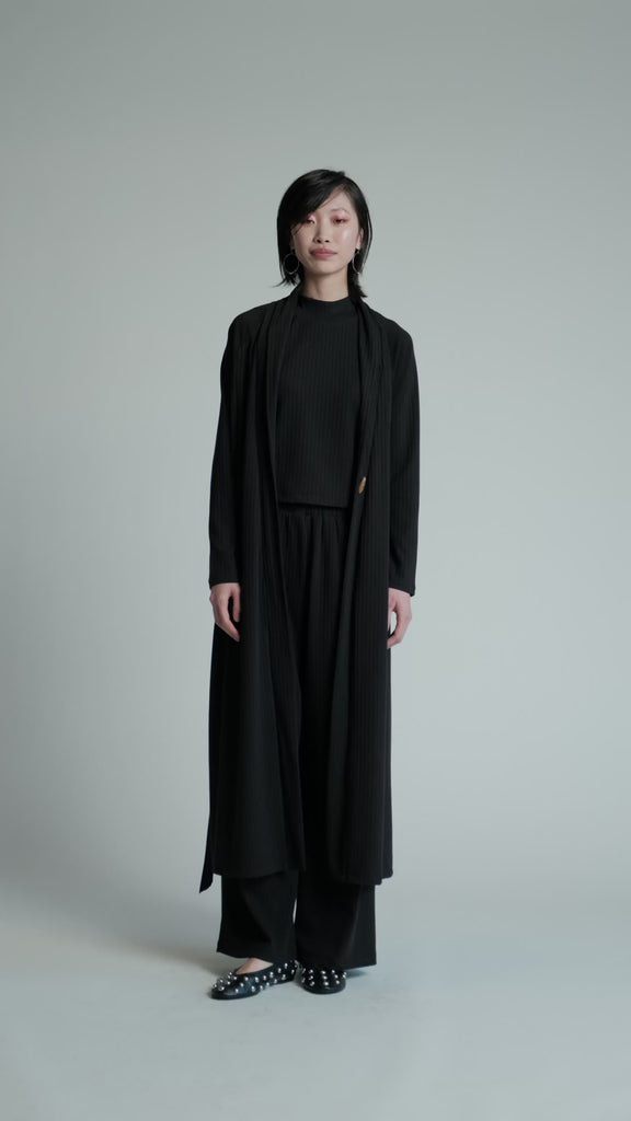 Video of a model in a studio wearing a black Support Cardi.