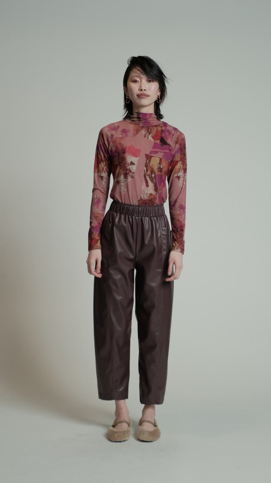 Video of a model in a studio wearing a pink print Aches top.